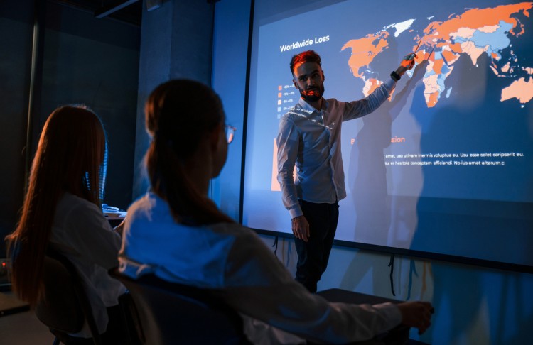 A disaster resilience professional points to a world map while giving a presentation.