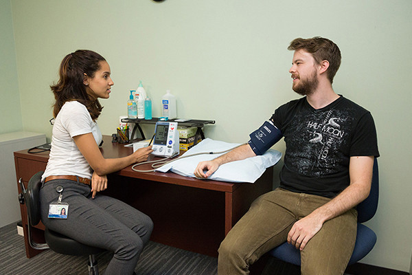 A clinician takes a young man's blood pressure