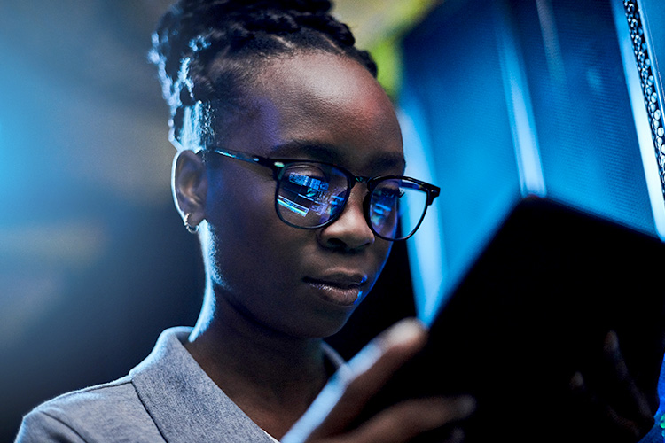 A woman wearing glasses looks at a tablet.